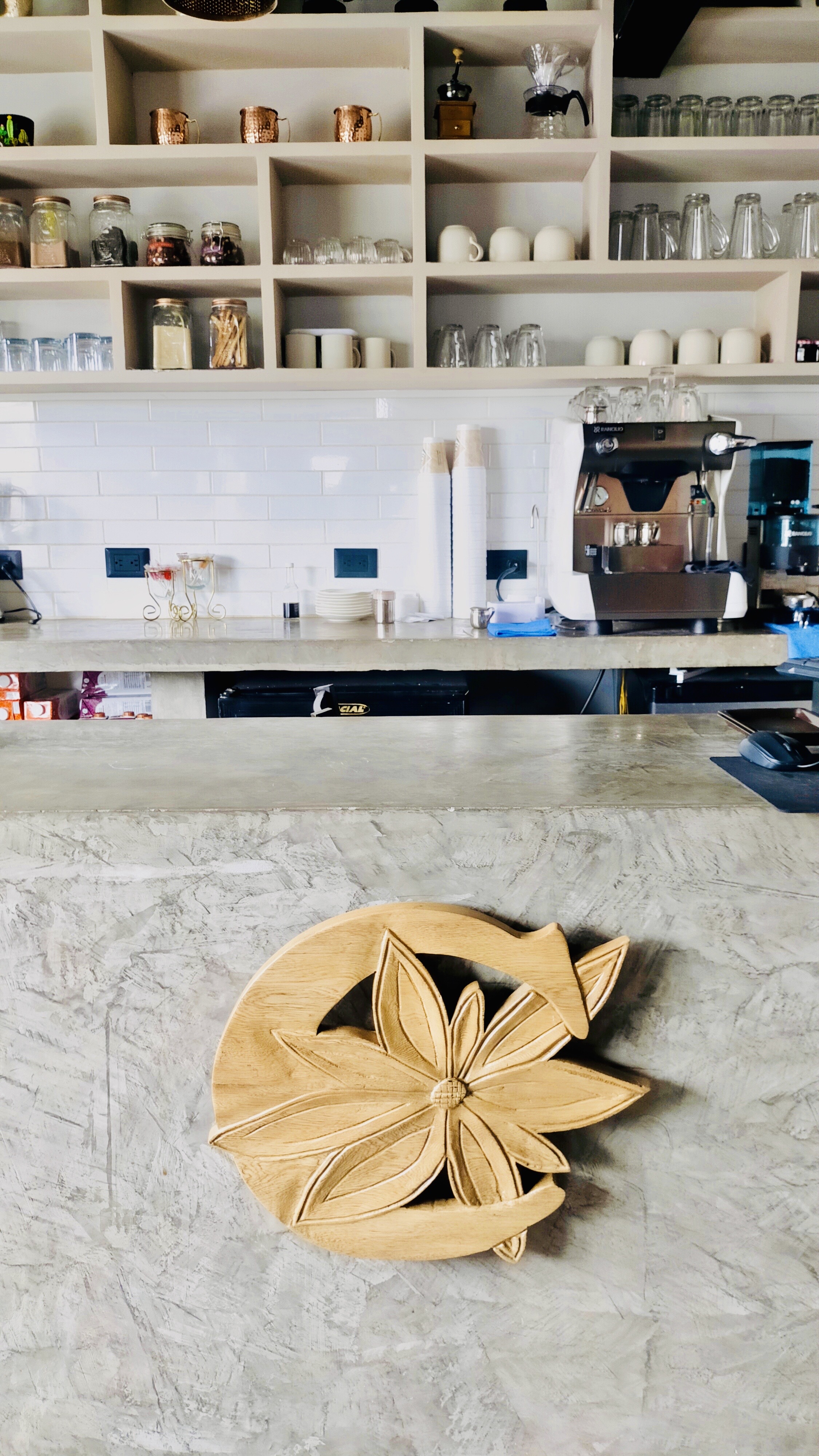 Interior del bar de Canela Café con estantes y la máquina Rancilio